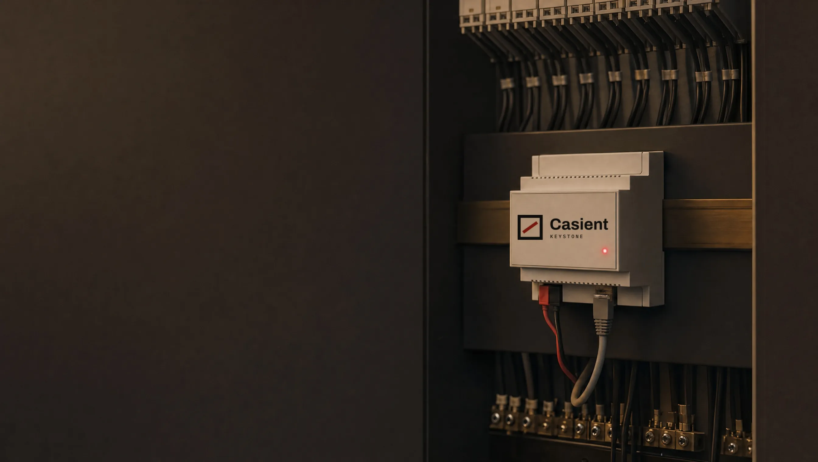 The Casient Keystone: a small DIN-rail unit labelled Casient Keystone, with a red and black KNX terminal, one network cable and a red status light, mounted in a tidy cabinet
